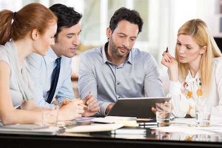 Hommes et femmes d'affaires discutant de rapports financiers sur une tablette avec leur comptable professionnel agréé